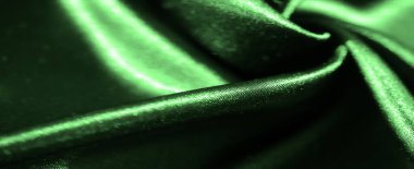Yumuşak dalgaları ve parlak dokusuyla yemyeşil saten kumaş, ışığı zarifçe yansıtıyor, kumaşın lüksünü ve pürüzsüzlüğünü akışkan kıvrımlarla arttırıyor..