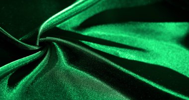 Yumuşak kıvrımlı parlak yeşil saten kumaş dalgalanan dalgalar yaratıyor, parlak dokusu kumaşın lüks ve zarif estetiğini artırmak için ışığı yansıtıyor..
