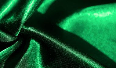 Yumuşak ışıkla aydınlanan yeşil saten kumaştan bulanık, canlı ve lüks bir doku yaratıyor, kıvrımlar ve zengin gölgeler, moda ve tasarım kavramları için ideal..