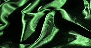 Akan kıvrımlı canlı yeşil saten kumaştan bir bulanıklık. Pürüzsüz, parlak yüzey karmaşık ışık ve gölgeleri yakalar, zengin, lüks bir doku ve zarif bir görsel görüntü yaratır..