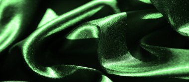 Bulanık yeşil saten kumaş sıvı yaratır. İnce gölgeler ve parlak ışık yansımalarıyla gelişen dalgalı dokular. Katlar lüks ve sofistike bir şekilde yayılan zarif, yumuşak bir desen oluşturuyor.