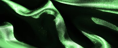 Parlak yeşil saten kıvrımlar, lüks dokuyu ve canlı rengi vurguluyor. Işığın etkileşimi düz kumaş yüzeyinde ince gölgeler ve gölgeler yaratır..
