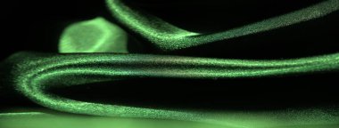 Yumuşak kıvrımlarla çekilen parlak yeşil saten kumaş bulanıklığı çarpıcı ışık vurgularıyla, malzeme akışının zenginliğini ve zarafetini gözler önüne seriyor..