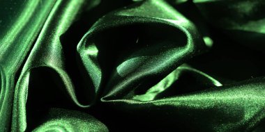 Doğal kıvrımlarla örtülmüş yeşil saten kumaş bulanıklığı, yumuşak ışık yansımalarıyla aydınlatılmış, kumaşın ipeksi yumuşak dokusuna derinlik ve boyut veren.