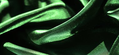 Bulanık yeşil saten kumaş karmaşık kıvrımları ve yumuşak dokuyu ortaya çıkarır. Pürüzsüz, parlak yüzey ince ışığı yansıtıyor. Lüks ve canlı bir kompozisyon yaratarak zarafetini vurguluyor..