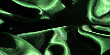 Yumuşak kıvrımlı yeşil saten kumaşın bulanıklığı, kumaşın yumuşak parıltısını ve dokusunu yakın çekim görüntüsünde yakalıyor canlı yeşil renk, kumaşın lüks ve parlak yüzeyini vurguluyor.