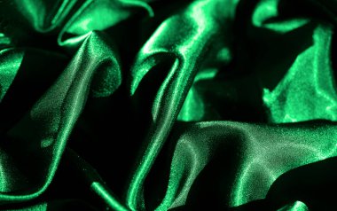 Karmaşık kıvrımlı canlı yeşil saten kumaştan bulanık, parlak yüzey ışığı çok güzel yakalıyor. Yakından bakınca kumaşın pürüzsüz ve lüks havası mükemmel.