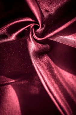 Yakından bakıldığında koyu kırmızı saten kumaş, karmaşık kıvrımlar ve yumuşak gölgeler yakalıyor, kumaşların lüks ve ipeksi dokusunu zengin, parlak bir kaplamayla renklendiriyor..