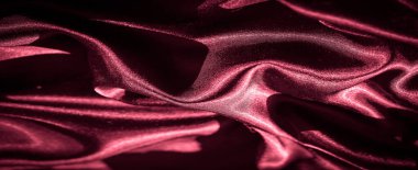 Görüntü, parlak bir parıltıyı düşük ışıkta yansıtan karmaşık kıvrımlı kırmızı saten kumaşı yakalıyor. Kumaşın pürüzsüz akışı soyut bir görsel ritim yaratır..