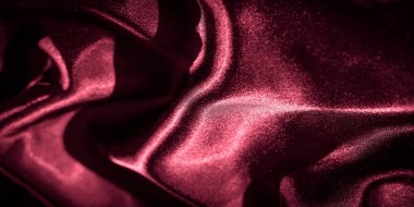 Koyu kırmızı saten kumaş, çarpıcı ışıklandırma kumaşların lüks dokusunu ve kıvrımlarını vurguluyor. Yumuşak, akışkan görünüş bir sofistike ve stil hissi yaratır..