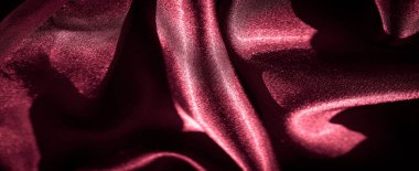 Işığı yakalayan ve parlak, ipeksi dokuyu yansıtan kalın kıvrımlı, koyu kırmızı saten kumaştan bir bulanıklık. Kumaşın lüks havası ve canlı kırmızı rengi kullanım için mükemmel hale getiriyor..