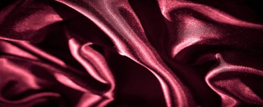 Pırıl pırıl parlayan, kırmızı saten kumaşlı bulanık, yumuşak dalgalarda ışığı yakalıyor. Kumaşın ipeksi dokusu ve lüks hissi son moda ve iç dekorasyon temaları için mükemmeldir..