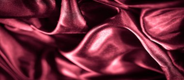 Pürüzsüz kıvrımları ve parlak yansıtıcı yüzeyi olan koyu kırmızı saten bir kumaşın bulanık yakın çekimi. Derin, zengin renkler, kumaşın lüksünü ve zarafetini vurgular.,