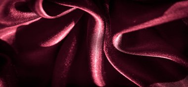 Zarif kıvrımlar ve parlak bir parıltı içeren koyu kırmızı saten kumaş. Lüks kumaş yüzeyi ışığı çok güzel yansıtıyor, varlıklı ve sofistike bir estetik yaratıyor..