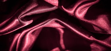 Dalgalanan dalgalarda koyu kırmızı renkli kumaş, ışık ve gölge oyunu parıltıyı ve kıvrımları arttırır, kompozisyonda hareket ve derinlik hissi yaratır..