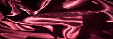 Akan kıvrımlara sarılı koyu kırmızı renkli saten kumaş bulanıklığı, ışık yansımalarıyla vurgulanmış. Pürüzsüz yüzey ve parlak bitiş gelişmişlik ve bolluk hissi uyandırıyor..