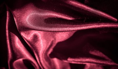 Kırmızı kıvrımlı bulanık saten dokusu: Buruşuk saten kumaşın soyut bir görünümü, parlak ışık yansımaları ile zengin kırmızı tonlarda narin kıvrımları gösteren, lüks, şık bir estetik sunan