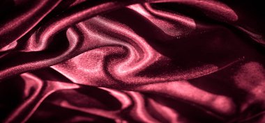 Bulanık kırmızı saten kumaş dalgaları: Kırışıklıklar ve koyu kırmızı saten dalgalar koyu renkli parlak bir doku oluşturur ve bu soyut kumaş çekimine derinlik katar.
