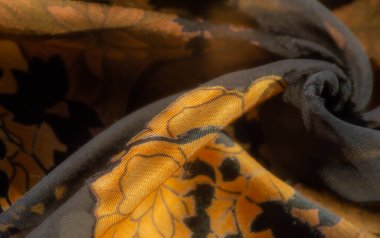 Parlak altın çiçekli zarif siyah kumaş bulanıklığı. Karmaşık kıvrımlar, kumaşa lüks ve sofistike bir cazibe veren bir ışık ve doku oyunu yaratıyor..