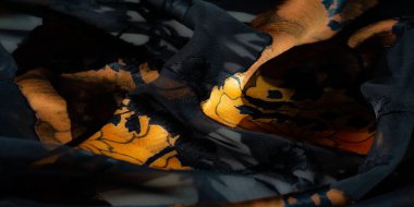 Görüntü. Yumuşak, şeffaf siyah kumaş, bu yakın plandaki canlı turuncu çiçeklerle çelişiyor. Kumaşın akışkanlığını ve çiçeklerin karmaşık çizgilerini vurguluyor..