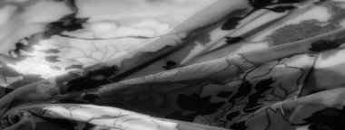 Soyut çiçek motifli koyu renkli çiçek kumaşı bulanıklığı. Zengin dokular ve yumuşak kumaş aydınlık ve karanlığın büyüleyici bir etkileşimini yaratarak tasarıma derinlik ve karmaşıklık katar..