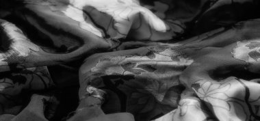 Bulanık etkisi bu gri pullu kumaştaki çiçek desenlerini vurguluyor. Çiçeklerin karmaşık siyah çizgileri bir zarafet ve doku hissi yaratarak zamansız bir estetik ekliyor.