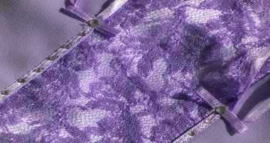 Bu mor dantel kumaşın karmaşık tasarımı yumuşak bir ışıltıyla geliştirilmiş örgü ve çiçek elementlerinin bir kombinasyonunu içeriyor. Tekstil, moda ve dekoratif amaçlar için ideal..