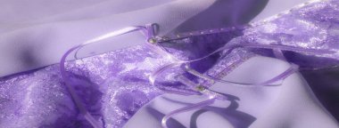 Hassas kurdele süslemeleriyle süslenmiş lavanta dantelli bulanık bir kumaş. Kumaş zarif bir şekilde kıvrılır. Işıldayan çiçekli dantelle renklendirilir..