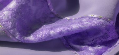 Narin kurdele aksanları ve boncuk süslemeleri olan yumuşak lavanta dantelli kumaş bulanıklığı. Dantel ışığın altında parıldıyor, romantik ve kadınsı bir atmosferde lüks bir his yaratıyor..