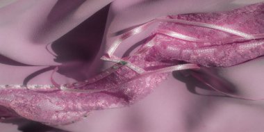 Karmaşık çiçek desenli, parıldayan pembe dantel kumaş ve küçük yeşil değerli taşlarla kaplı narin, ışıltılı bir şerit. Doku zarafet ekler..