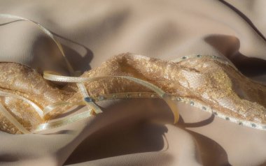 Yumuşak, akışkan kıvrımlarla vurgulanmış bej kumaştan bir bulanıklık. Işık ve gölge arasındaki etkileşim, maddenin lüks dokusunu ve ince işçiliğini geliştirir..