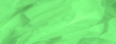 Bulanık yeşil saten kumaş katmanları soyut bir düzenleme oluşturarak tekstilin sıvı hareketini yakalar. Yumuşak, ipeksi yüzey ışığı nazikçe yansıtır ve dinginlik hissi yaratır..