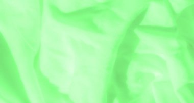 İnce kıvrımlar ve akış çizgileri gösteren ince yeşil kumaş bulanıklığı. Yumuşak ışık yüzeyden yansıyarak derinlik ve hareket yanılsaması yaratarak kumaşın doğal güzelliğini arttırır..