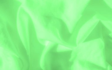 Yumuşak kıvrımlı yeşil saten kumaş ve narin ışıkla güçlendirilmiş düz dokular. Soyut tasarım ve nazik akış arka plan veya tasarım unsurları için görsel olarak sakinleştirici bir tekstil ideali oluşturur..