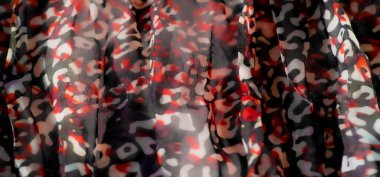 Görüntü: Kırmızı, siyah ve beyaz soyut desenli, ince ışık yansımalarıyla pürüzsüz akan bir kumaş. Katmanlı doku maddenin akışkan hareketine boyut ekler..