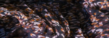 Karmaşık kırmızı, siyah ve beyaz soyut desenli yumuşak kumaş bulanıklığı. Tasarım dinamik görünüyor, canlı renkler maddenin içinde pürüzsüz bir şekilde harmanlanıyor..