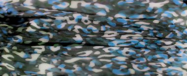 Mavi, yeşil ve siyah desenlerin canlı bir karışımı yumuşak kumaşa sorunsuzca akıyor, akışkan dokular ve yumuşak kıvrımlarla büyüleyici bir soyut tasarım yaratıyor..