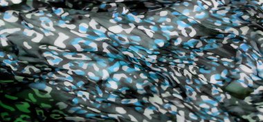 Mavi, beyaz ve yeşil tonlarda kamuflaj desenli yumuşak, dalgalı kumaş bulanıklığı. Soyut desen, hem modern hem de dinamik, arka plan veya tekstil tasarım temaları için mükemmel bir görsel doku yaratır..