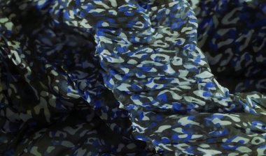 Siyah arka planda mavi, yeşil ve beyaz soyut desenli kumaşın pürüzsüz ve yumuşak dokusunu bulanıklaştır. Dinamik tasarım akıcılık ve modern moda estetiğini çağrıştırıyor.,