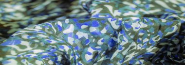 Görüntü. Yüzeyde mavi, beyaz ve yeşil tonlarının aktığı soyut kamuflaj esinlenilmiş güzel bir kumaş. Yumuşak kıvrımlar dinamik bir görsel akış yaratır.