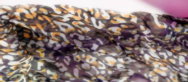 Mor, sarı ve kahverengi tonlarında soyut desenlerle akan kumaş bulanıklığı. Karmaşık kıvrımlar dinamik ve modern bir görünüm sunan canlı ve dokulu bir yüzey oluşturuyor..