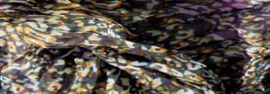 Mor, yeşil ve kahverengi şekilli bulanık kumaş tasarımı. Karmaşık ve canlı bir desen oluşturuyorlar. Kumaşın akışkan kıvrımları hareket ve derinlik hissi yaratır..