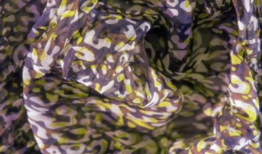 Mor, sarı ve kahverengi soyut şekillerin bulanıklığı kumaşı dinamik ve girdap şeklinde kaplar. Kalın renkler ve karmaşık tasarım ona modaya uygun bir estetik kazandırıyor..