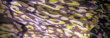 Kıvrımlı mor ve sarı soyut tasarımların bulanıklığı, katmanlı desenler ve canlı renklerle görsel dinamik ve sanatsal bir kumaş bileşimi oluşturur..