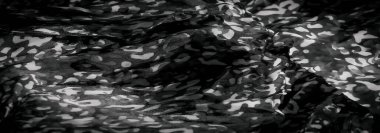 Soyut desenleri ve yumuşak kıvrımları olan gri tonlu bir kumaşın bulanık görüntüsü dinamik ve sanatsal bir görsel etki yaratıyor. Işık ve karanlık tonlar arasındaki zıtlık derinlik ve boyut ekler..