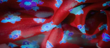 Görüntü - koyu kırmızı kumaş, zengin bir arkaplanda göze çarpan canlı mavi ve mor çiçekler sergiliyor. Malzemenin doğal kıvrımları dinamik bir akış yaratarak derinlik ve zarafet ekler..