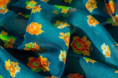 Dağılmış turuncu ve yeşil çiçeklerle süslenmiş bu yumuşak mavi kumaşın enerjik tasarımı bulanıklaşır. Neşeli renk paleti her türlü tekstil koleksiyonuna ya da iç tasarım projesine enerji katar.