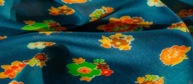 Dağılmış turuncu ve yeşil çiçeklerle süslenmiş bu yumuşak mavi kumaşın enerjik tasarımı bulanıklaşır. Neşeli renk paleti her türlü tekstil koleksiyonuna ya da iç tasarım projesine enerji katar.