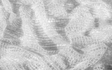 Karmaşık desenleri olan bulanık beyaz dantel kumaş. Yumuşak örtülmüş. Parlak ve ruhani bir doku oluşturuyor. Karmaşık örgü ve ince ışık zarafet ve inceliği çağrıştırıyor..