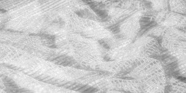 Karmaşık beyaz dantel kumaşın bulanık görüntüsü ince desenli narin bir desen sergiliyor dantel iplikler parıldıyor, moda ya da düğün tasarımları için ideal yumuşak, zarif bir görünüm yaratıyor.